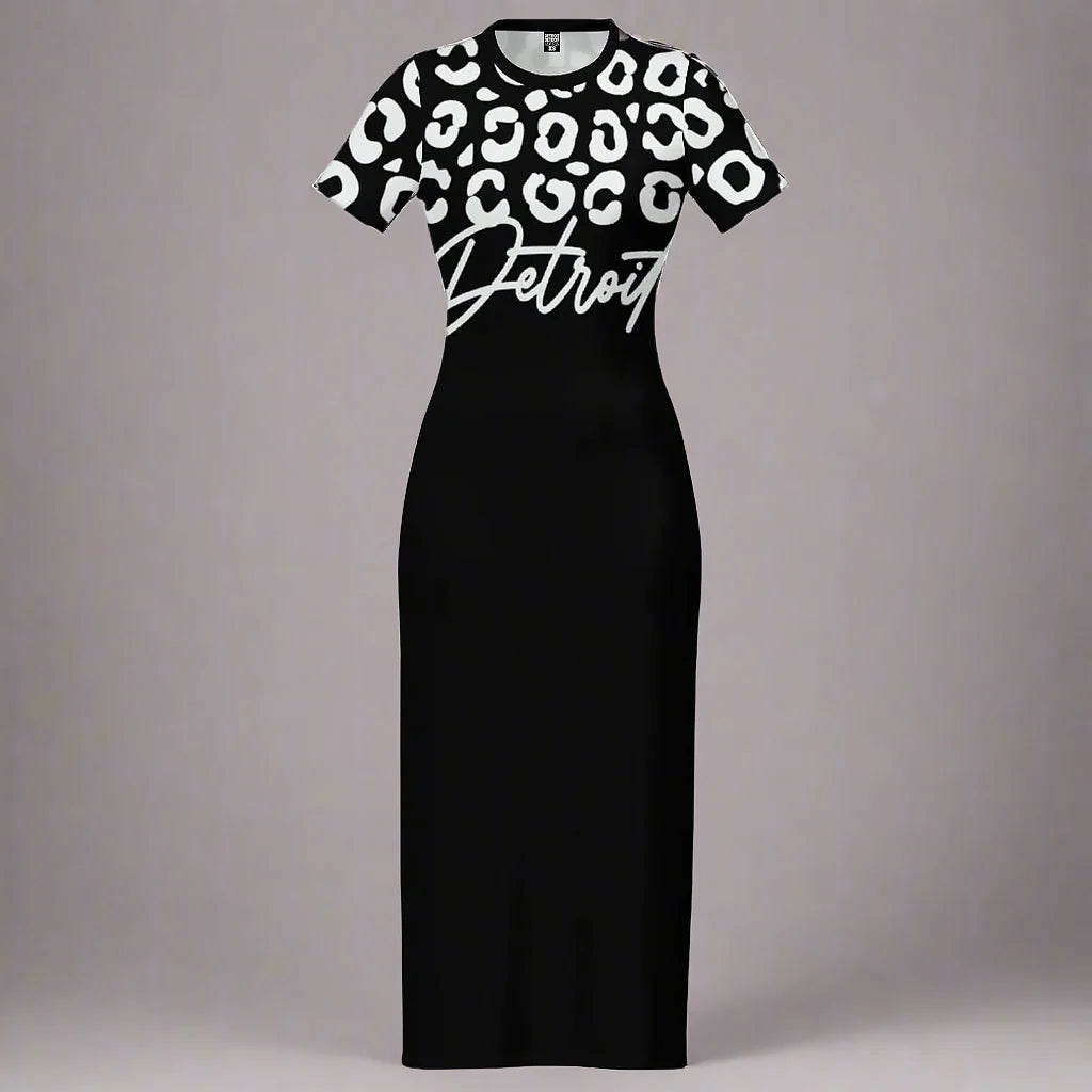 Black fitted maxi dress displayed flat against a gray background. The top portion of the dress features a bold white leopard print pattern, while the lower portion remains solid black. The word 'Detroit' is printed in large white cursive font across the chest, overlapping slightly between the patterned and solid sections. The dress has short sleeves and a crew neckline
