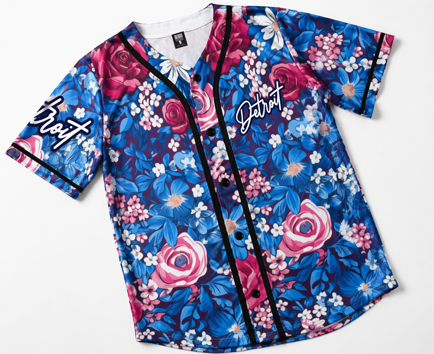 Flat lay detail of women’s Detroit floral baseball jersey featuring blue and pink flower pattern, button front, and black piping on white background