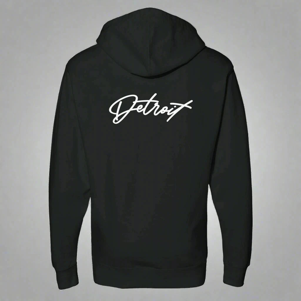 Back view of a black hoodie featuring the word “Detroit” in white script across the upper back, displayed against a neutral gray background.