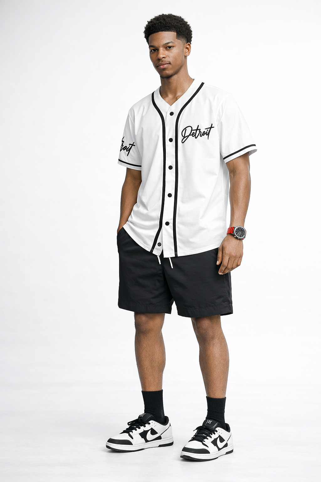 Man wearing white Detroit baseball jersey with black shorts and black and white sneakers, full body streetwear outfit