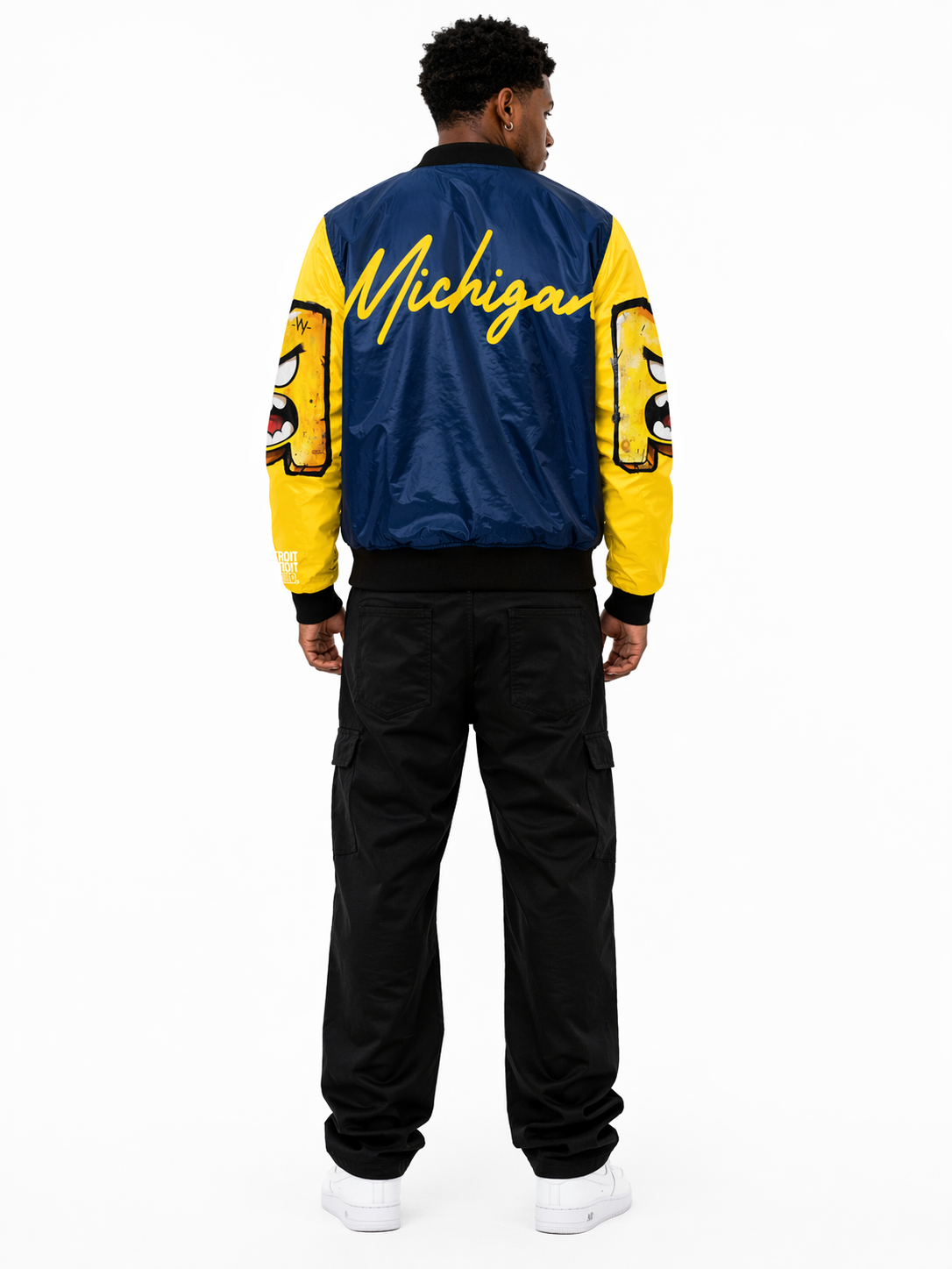 Back view of male model wearing Michigan National Champions 2026 bomber jacket in navy and maize, Detroit streetwear varsity jacket with bold Michigan script