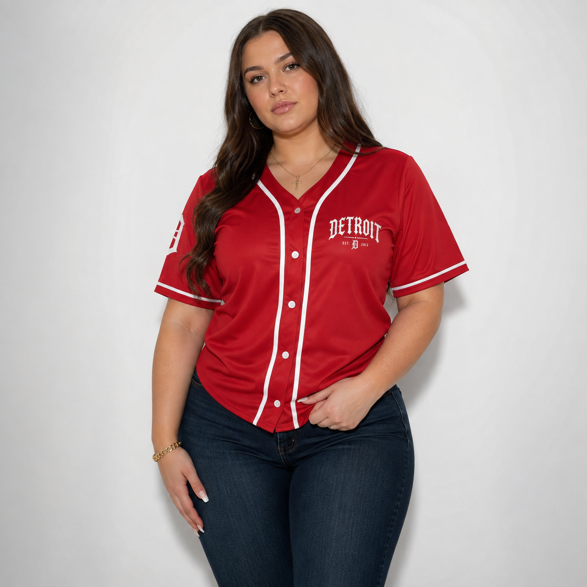A woman modeling a red Detroit Tigers baseball-style jersey with white trim and buttons, paired with dark blue jeans, against a plain light gray studio background.