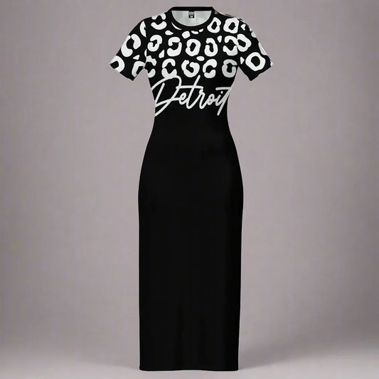 Black fitted maxi dress displayed flat against a gray background. The top portion of the dress features a bold white leopard print pattern, while the lower portion remains solid black. The word 'Detroit' is printed in large white cursive font across the chest, overlapping slightly between the patterned and solid sections. The dress has short sleeves and a crew neckline