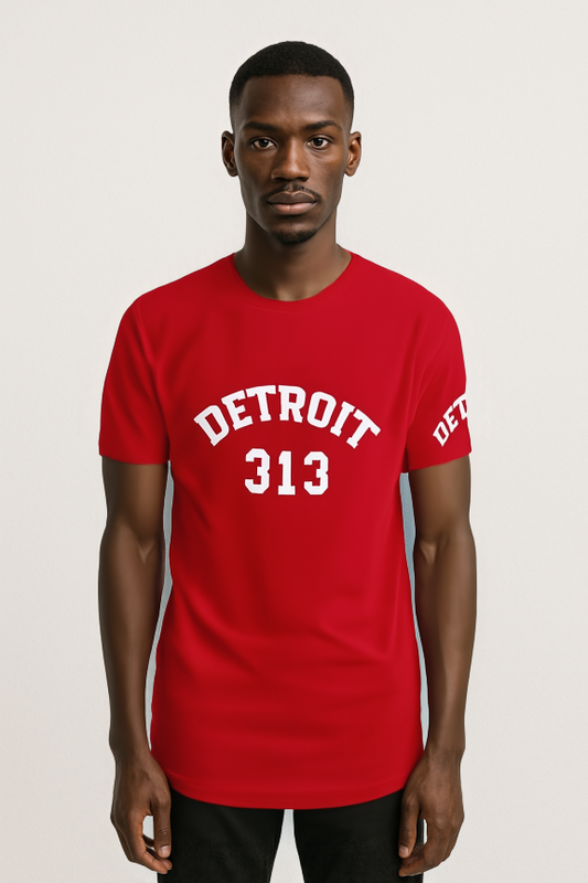 "A man wearing a bright red t-shirt with white text. The front of the shirt features the word 'DETROIT' in bold, arched capital letters above the number '313'. The left sleeve also has the word 'DETROIT' printed in white. The man stands against a plain light background, facing forward with a neutral 