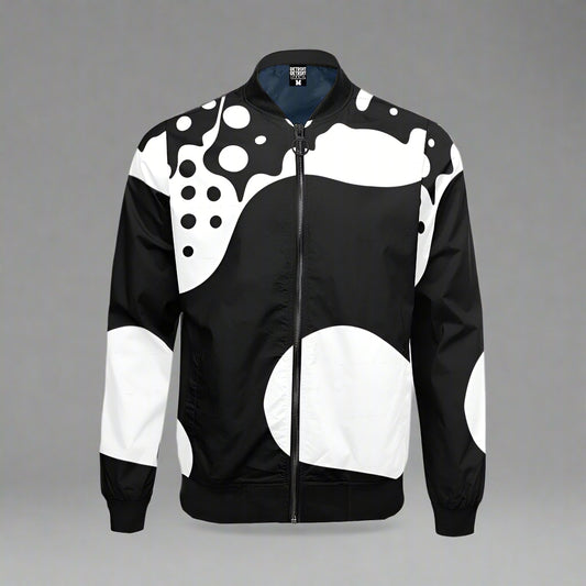 Black and white zip-up bomber jacket displayed flat against a gray background. The jacket features an abstract pattern with large white circles, flowing curves, and scattered black dots across the front, sleeves, and shoulders. It has a black collar, waistband, and cuffs, with a full-length black zipper.