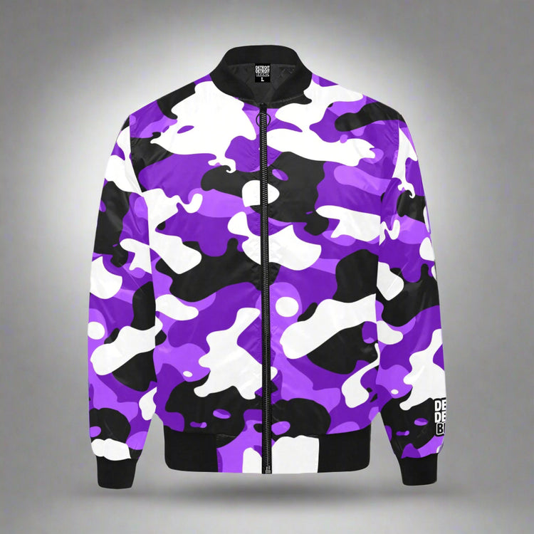 Bomber jacket displayed flat against a gray background. The jacket features a bold camouflage pattern in shades of purple, black, and white. It has a black zipper down the center, black ribbed collar, cuffs, and waistband. The sleeve includes a small white text logo near the wrist.