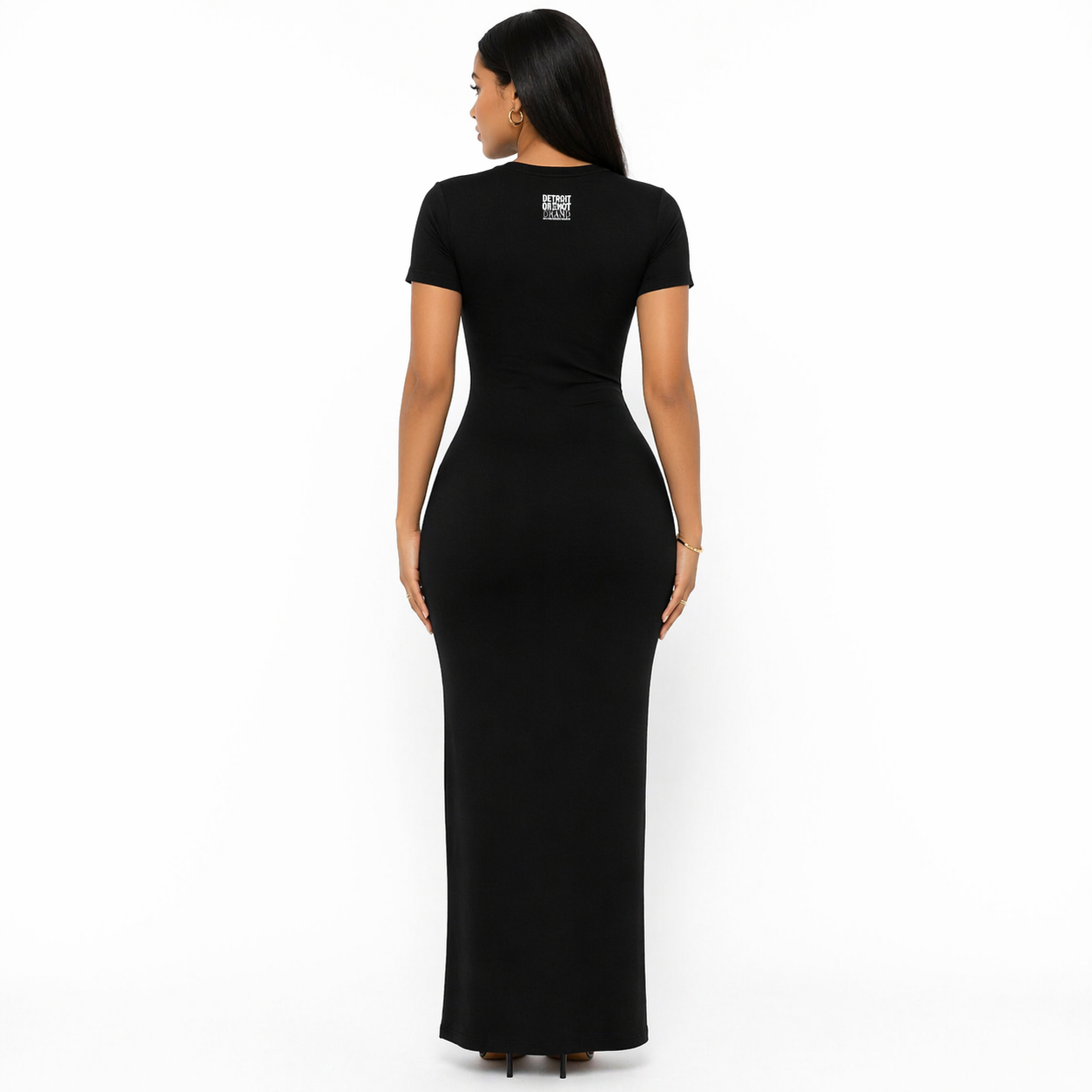 Back view of a female model wearing a fitted black Detroit 313 maxi dress with short sleeves, featuring a small Detroit Detroit Brand logo on the upper back, photographed on a clean white background.