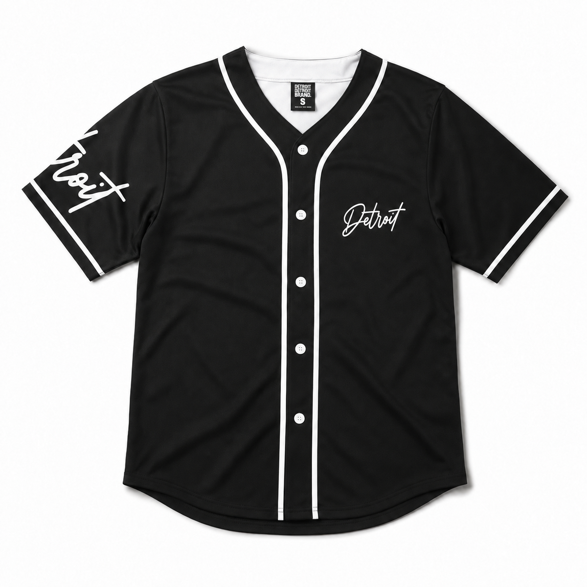 Front flat lay of a black Detroit baseball jersey with white piping, white buttons, white interior neckline, and Detroit script graphics on a white studio background.