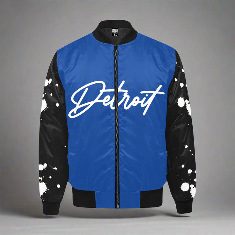 Blue Detroit bomber jacket with black sleeves featuring white paint-splatter design and bold white Detroit script on the front