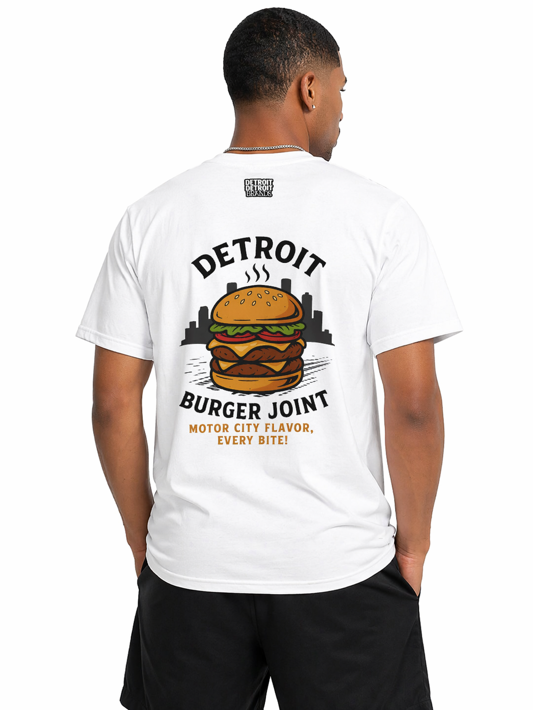 Back view of man wearing white Detroit Burger Joint t-shirt with large burger graphic and Detroit skyline design, casual streetwear outfit