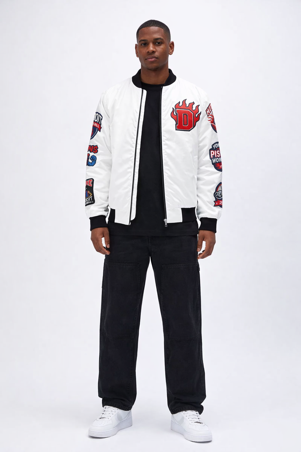 Person wearing a white 'Detroit Pistons' bomber jacket with patches on sleeve, black pants, and white sneakers on a white background