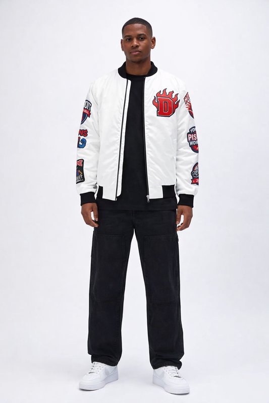Person wearing a white 'Detroit Pistons' bomber jacket with patches on sleeve, black pants, and white sneakers on a white background