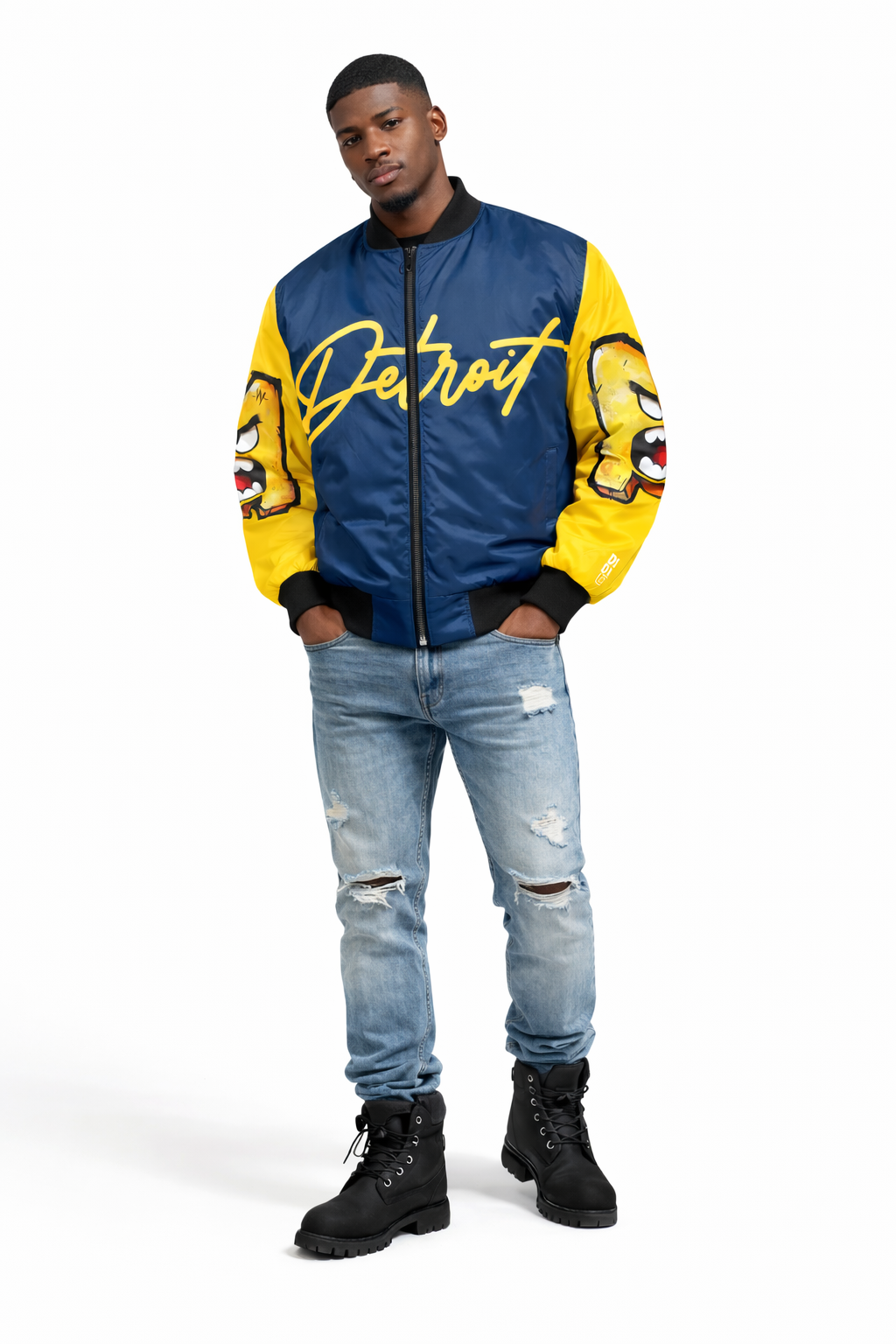 Man wearing a blue and yellow 'U of M' jacket with 'Detroit' text, ripped jeans, and black boots on a white background