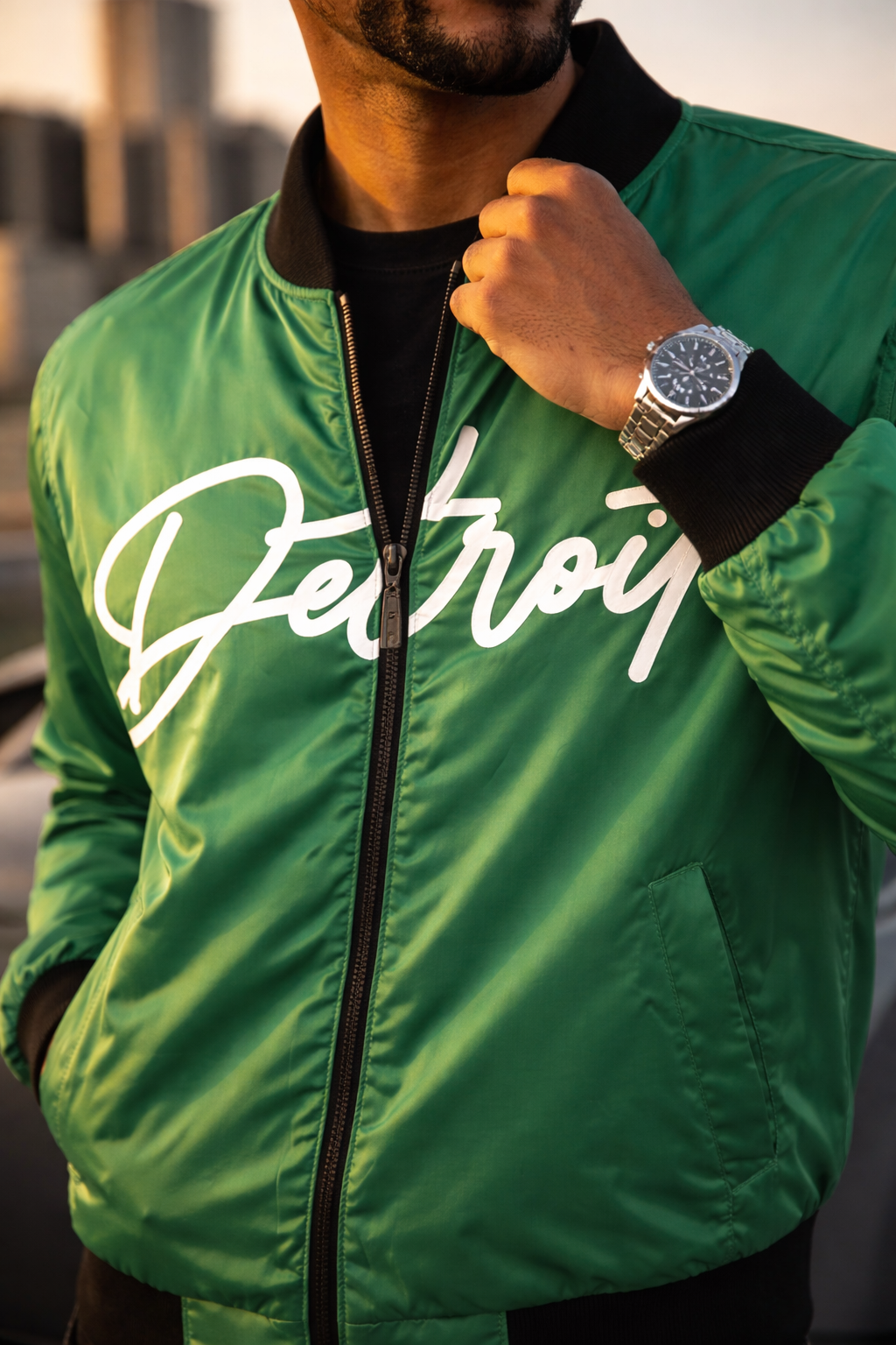 Person wearing a green jacket with 'Detroit' printed on it, holding the jacket collar.