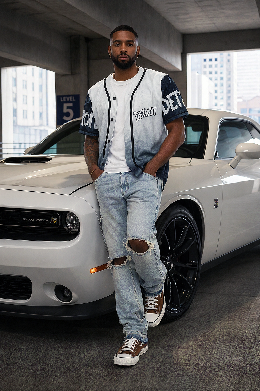 Man wearing Detroit grey and black baseball jersey leaning against white Dodge Challenger Scat Pack in parking garage, urban streetwear lifestyle