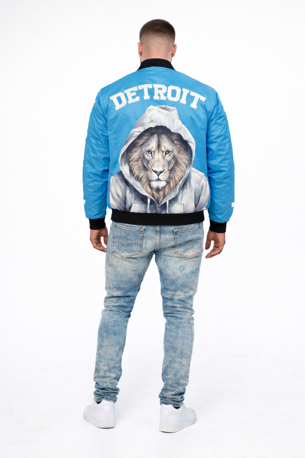 Person wearing a blue bomber jacket with a lion graphic and 'Detroit' text on the back, standing against a white background.