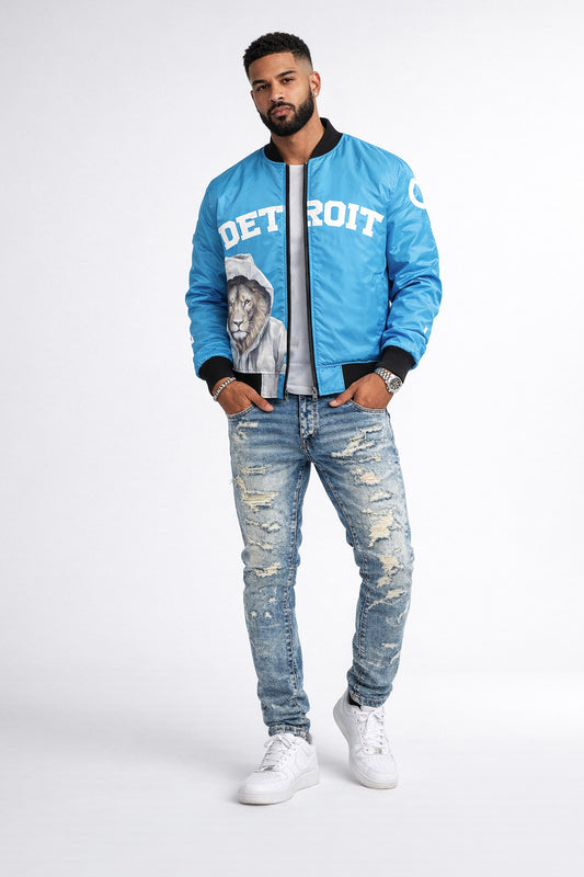 Man wearing a blue bomber jacket with 'Detroit' and a lion graphic, standing against a white background