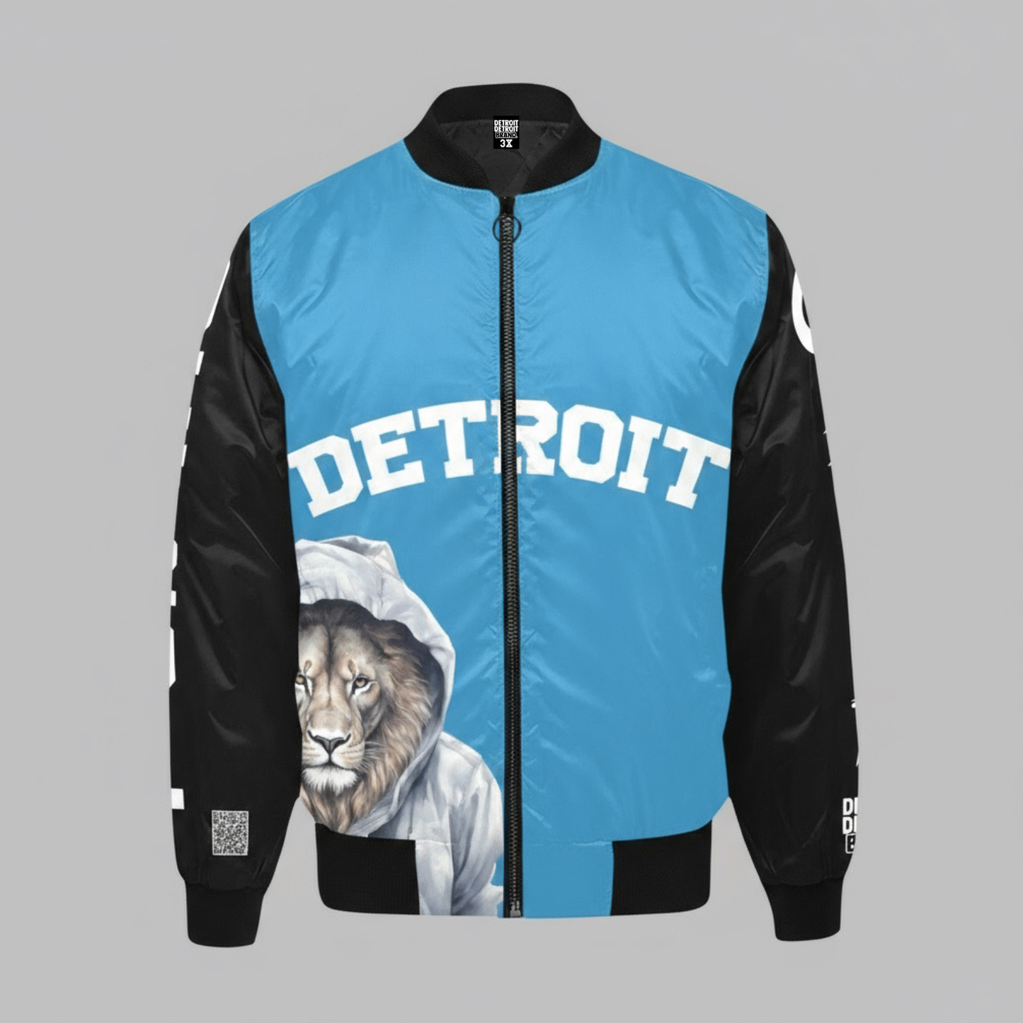 Blue and black bomber jacket featuring a large white “Detroit” text across the chest and a detailed illustration of a Detroit Lion wearing a hoodie on the lower front, with black sleeves and ribbed cuffs.