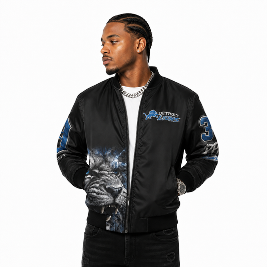 Male model wearing a black Detroit Lions bomber jacket with a silver Cuban link on a white studio background