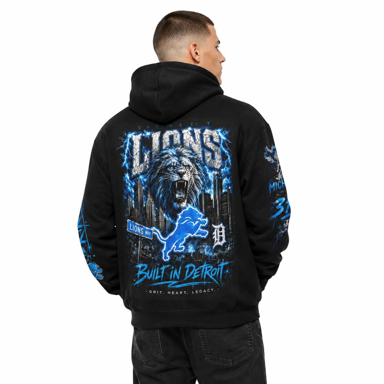 Male model wearing a black Detroit Lions-inspired hoodie featuring a large Honolulu blue lion, Detroit skyline, Lions Way sign, and Built in Detroit back graphic.