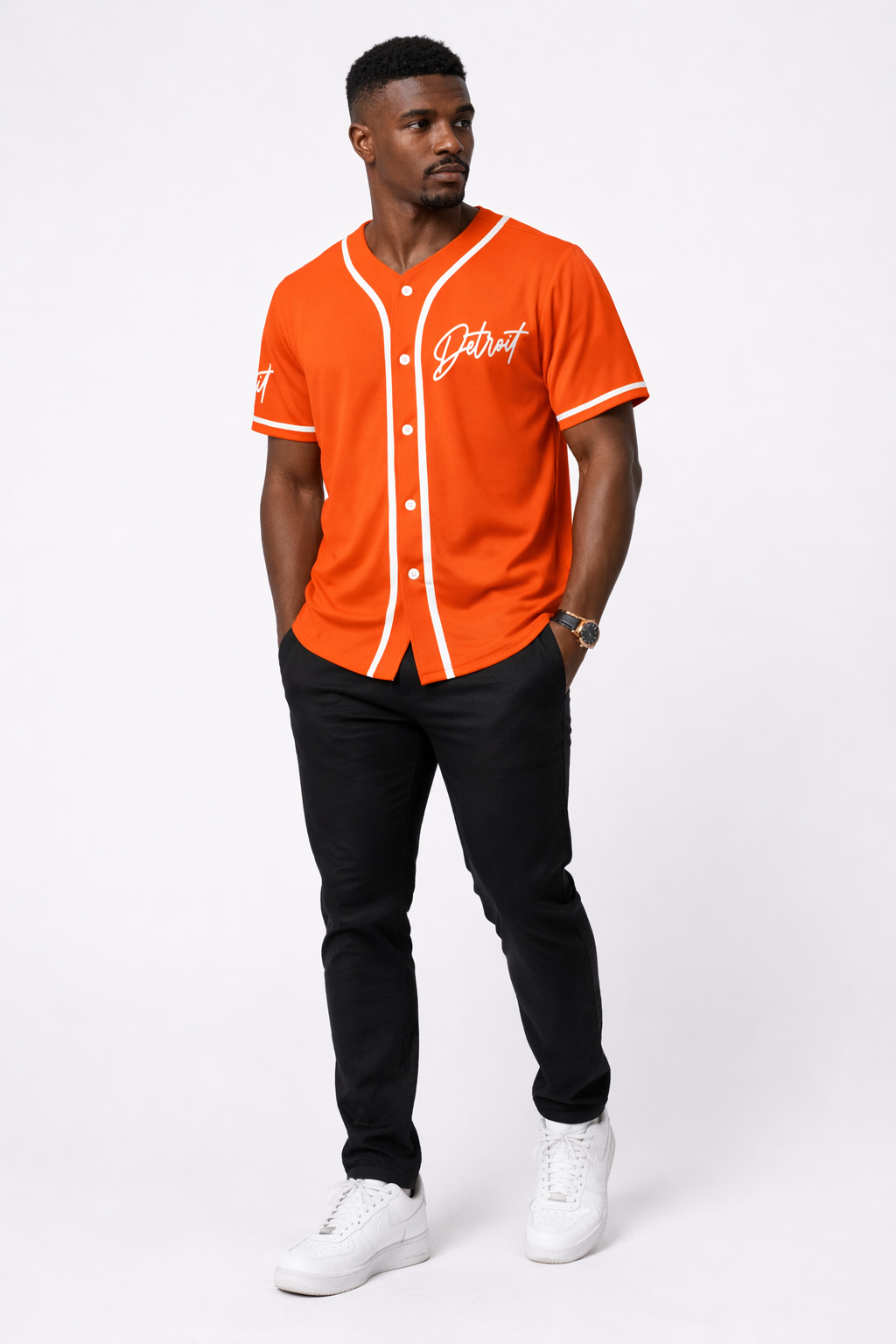 Man wearing orange Detroit baseball jersey with white piping, styled with black pants and white sneakers, full body front view