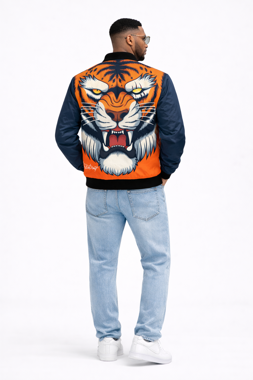 Person wearing a jacket with a tiger design on the back, standing against a white background