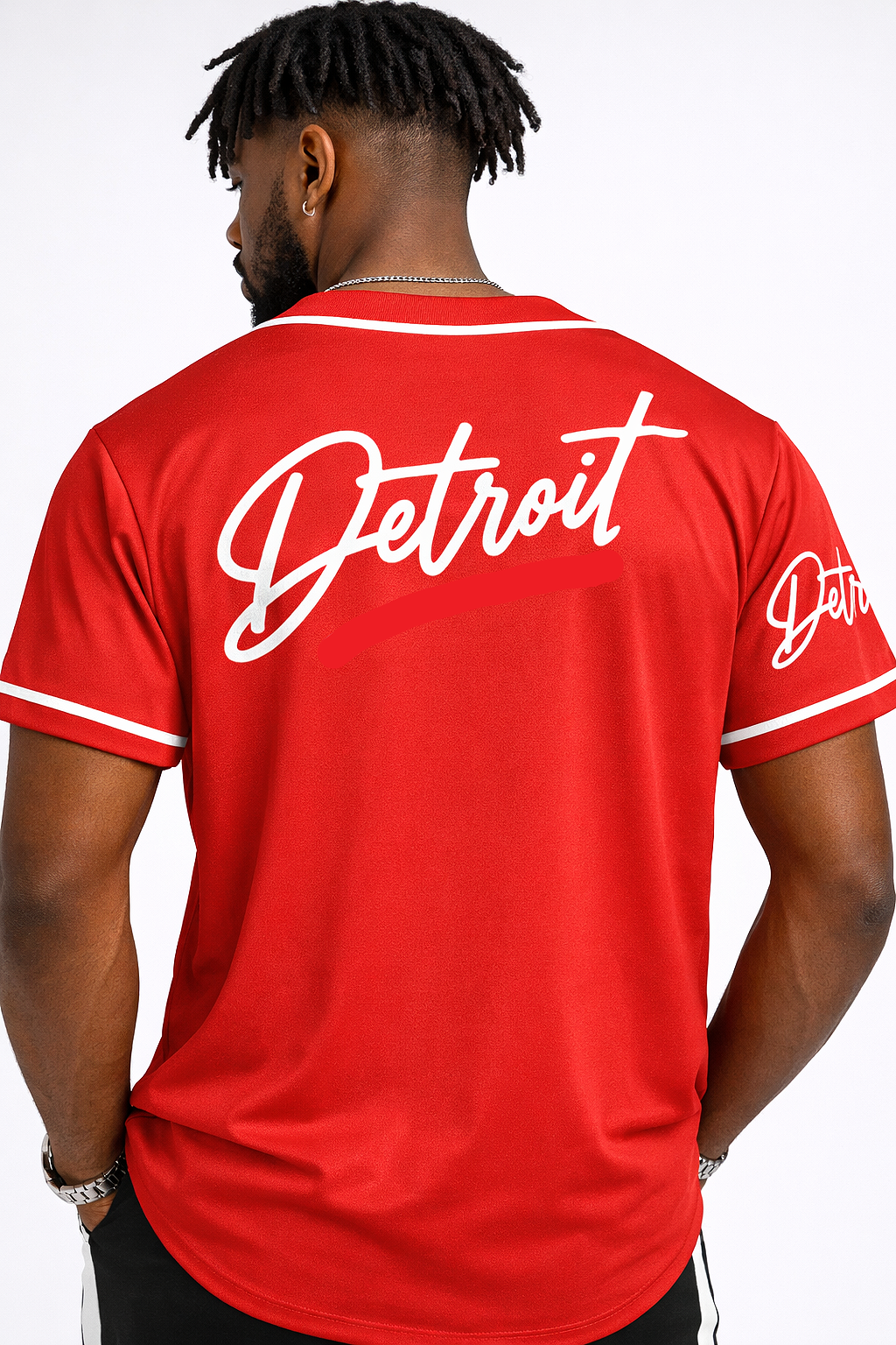Full body back view of male model wearing red Detroit script baseball jersey showing rear design and fit with black pants and sneakers