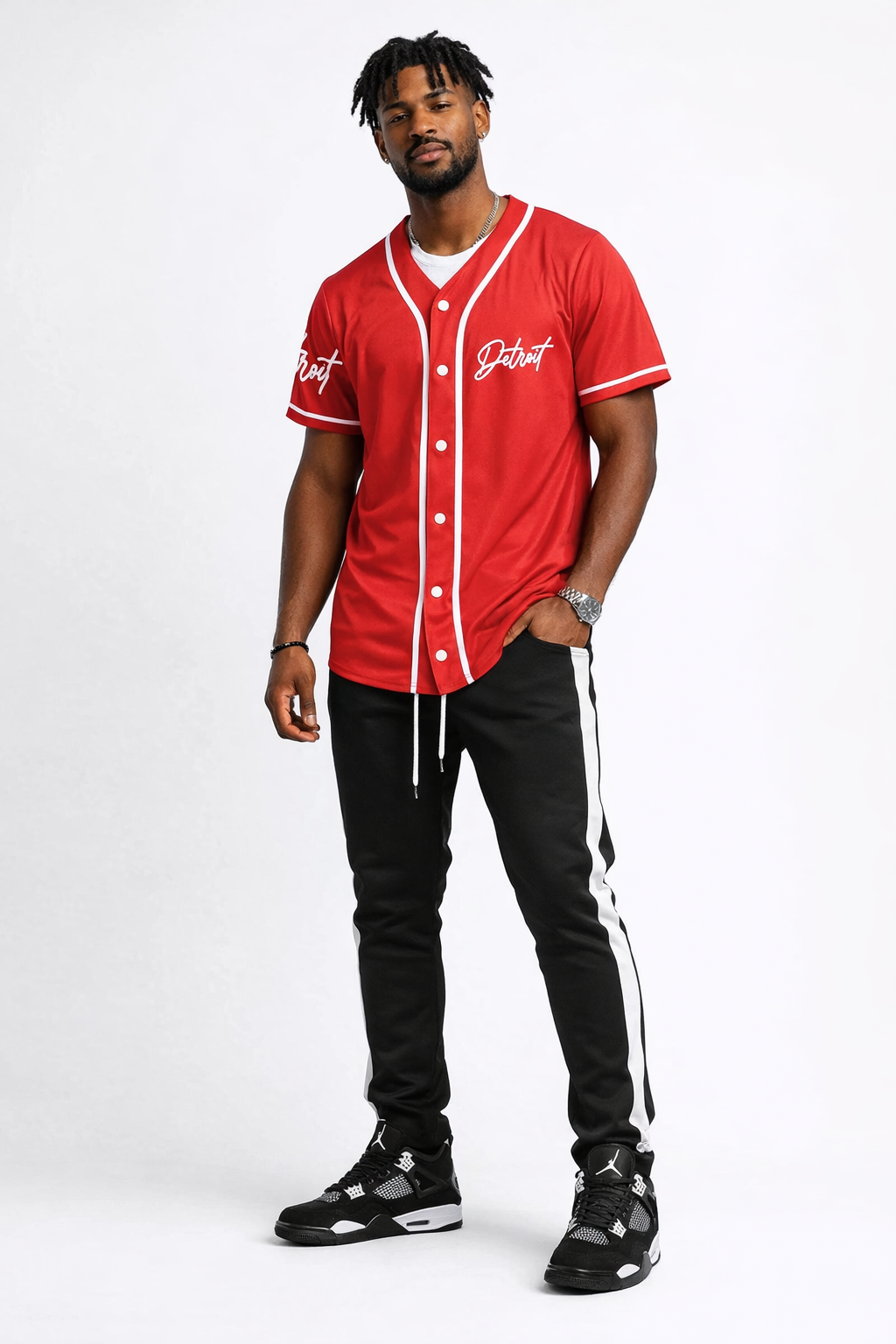 Full body front view of male model wearing red Detroit script baseball jersey styled with black pants and sneakers on a white background