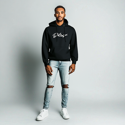 Man wearing a black hoodie with white “Detroit” script logo on the chest, paired with light blue ripped jeans and white sneakers, standing against a light gray background.