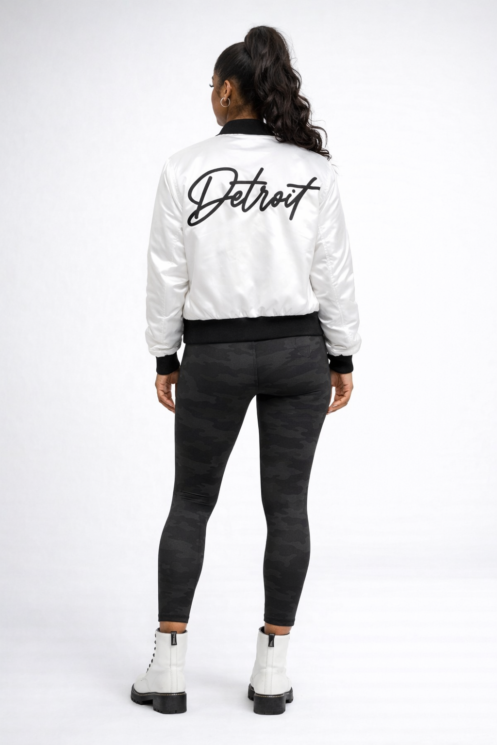 Person wearing a white jacket with 'Detroit' printed on the back, standing against a white background.