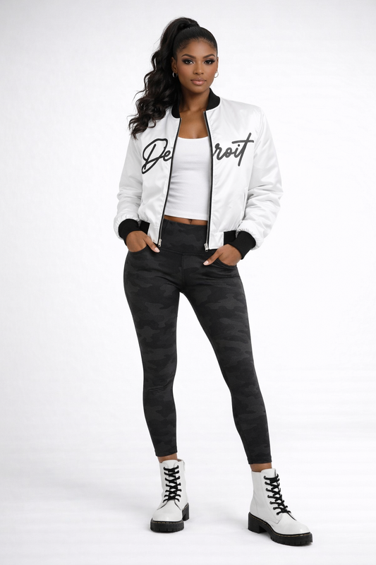 Woman wearing a white jacket with 'Detroit' text, white top, black pants, and white boots on a white background