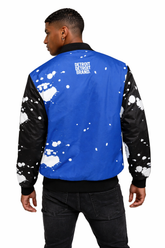 Back view of brown skin male model wearing Detroit Splatter Bomber Jacket showing Detroit Detroit Brand logo with paint splatter design on white background
