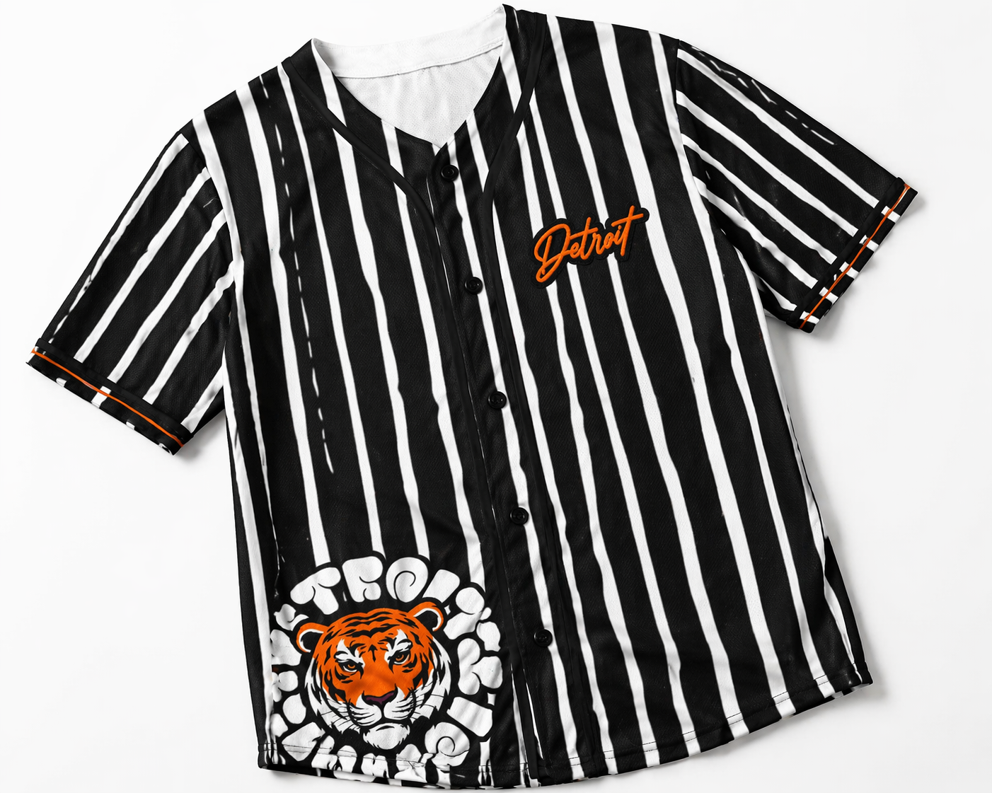 Flat lay detail shot of a black and white striped Detroit baseball jersey showing orange Detroit script logo, front buttons, vertical stripe pattern, and tiger graphic on a clean white background