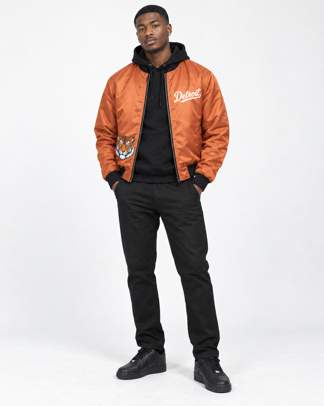 Male model wearing orange Detroit Tiger 1701 bomber jacket with black hoodie