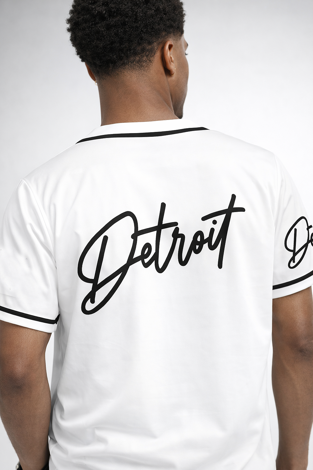 Back view of men’s white Detroit baseball jersey featuring large Detroit script logo and black trim
