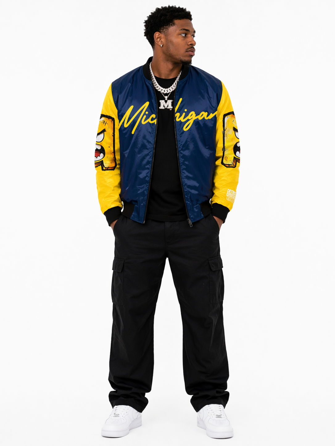 Male model wearing Michigan National Champions 2026 bomber jacket front view with silver chains, premium Detroit streetwear varsity jacket navy and yellow