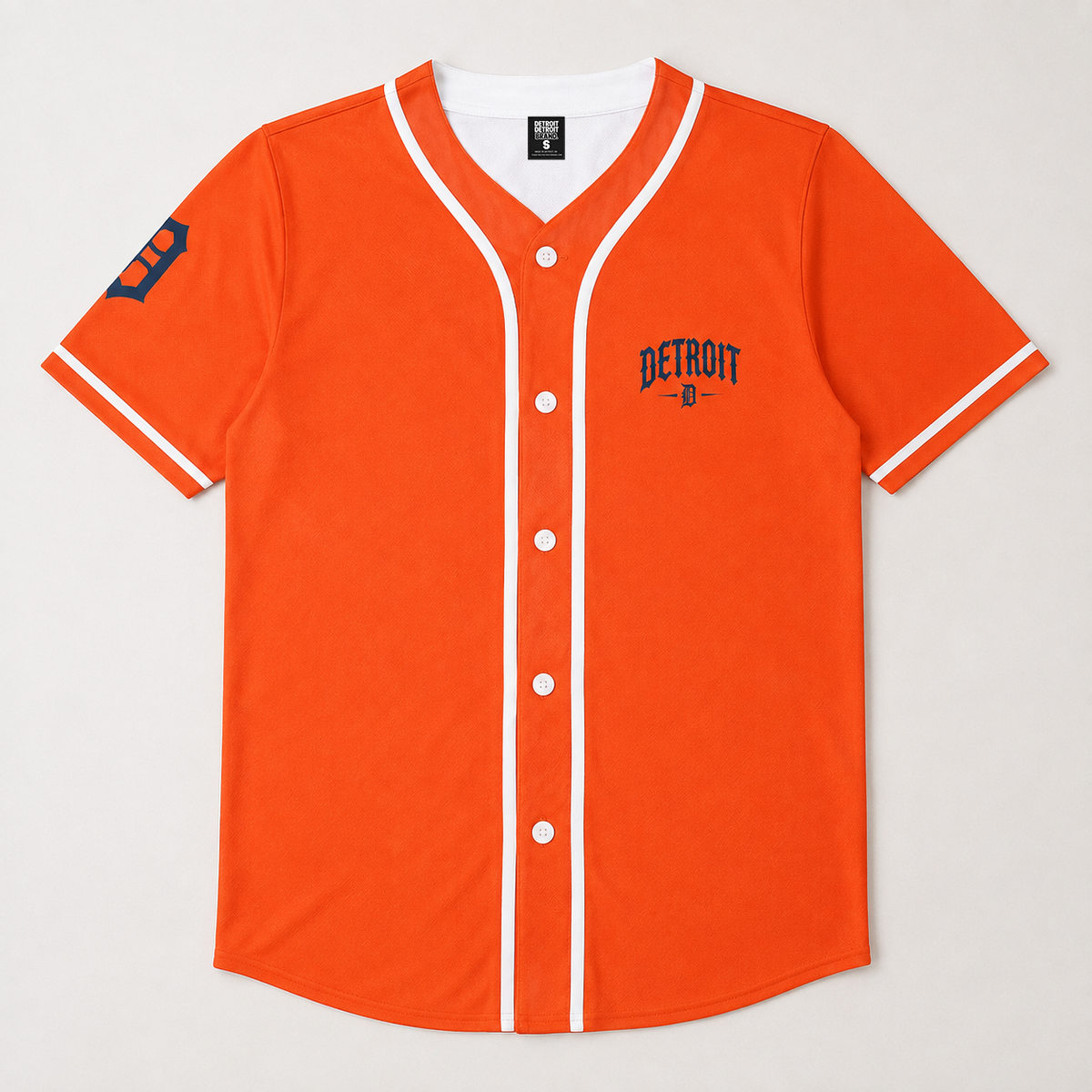 Bright orange Detroit Tigers baseball-style jersey with white trim, white snap buttons, a navy blue 'DETROIT' logo on the left chest, and a navy blue 'T' on the sleeve, shown flat against a light gray background.