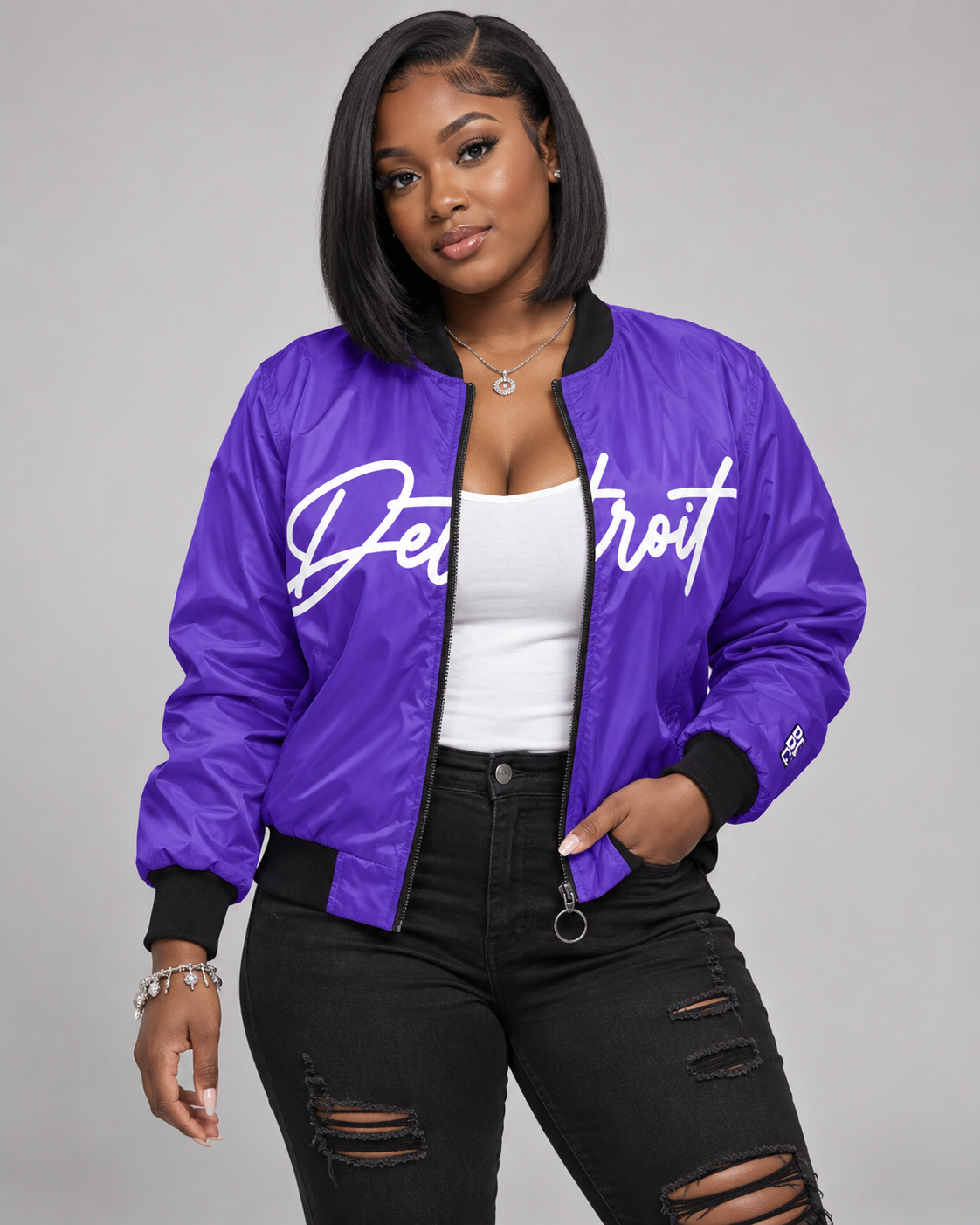 Female model wearing purple Detroit Script Bomber Jacket open over a white tank with black jeans
