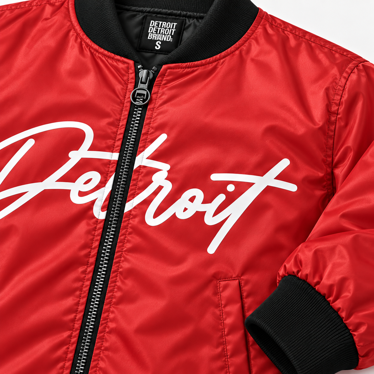     Close-up of red Detroit Script Bomber Jacket showing white Detroit lettering, zipper, black collar and polyester fabric