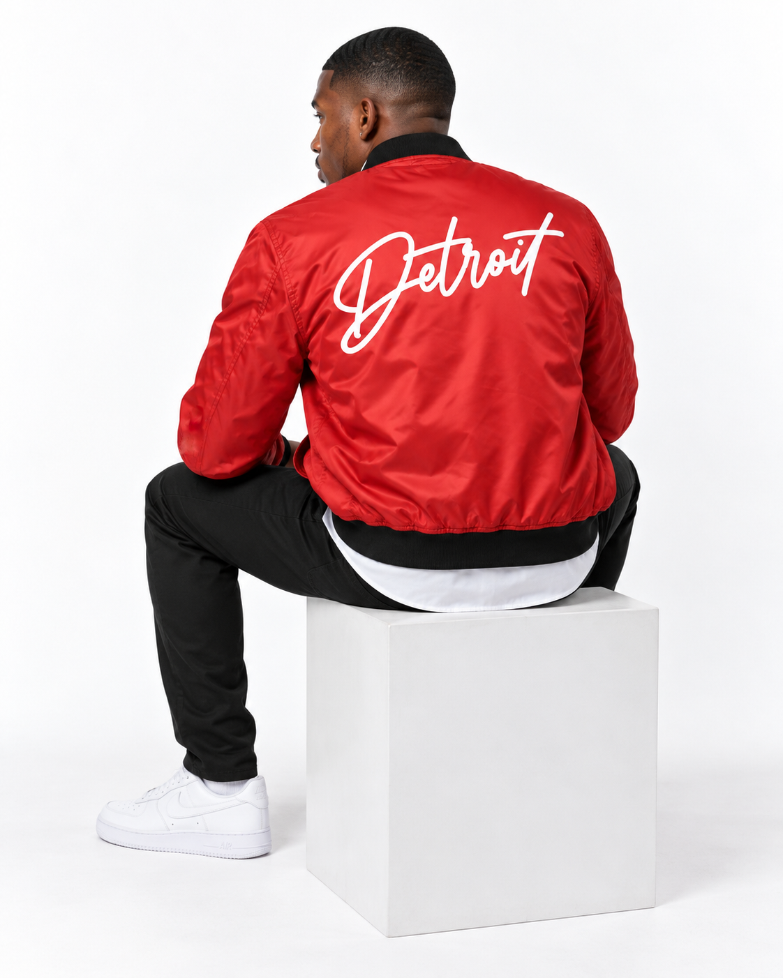     Back view of male model wearing red Detroit Bomber Jacket with large white Detroit script graphic
