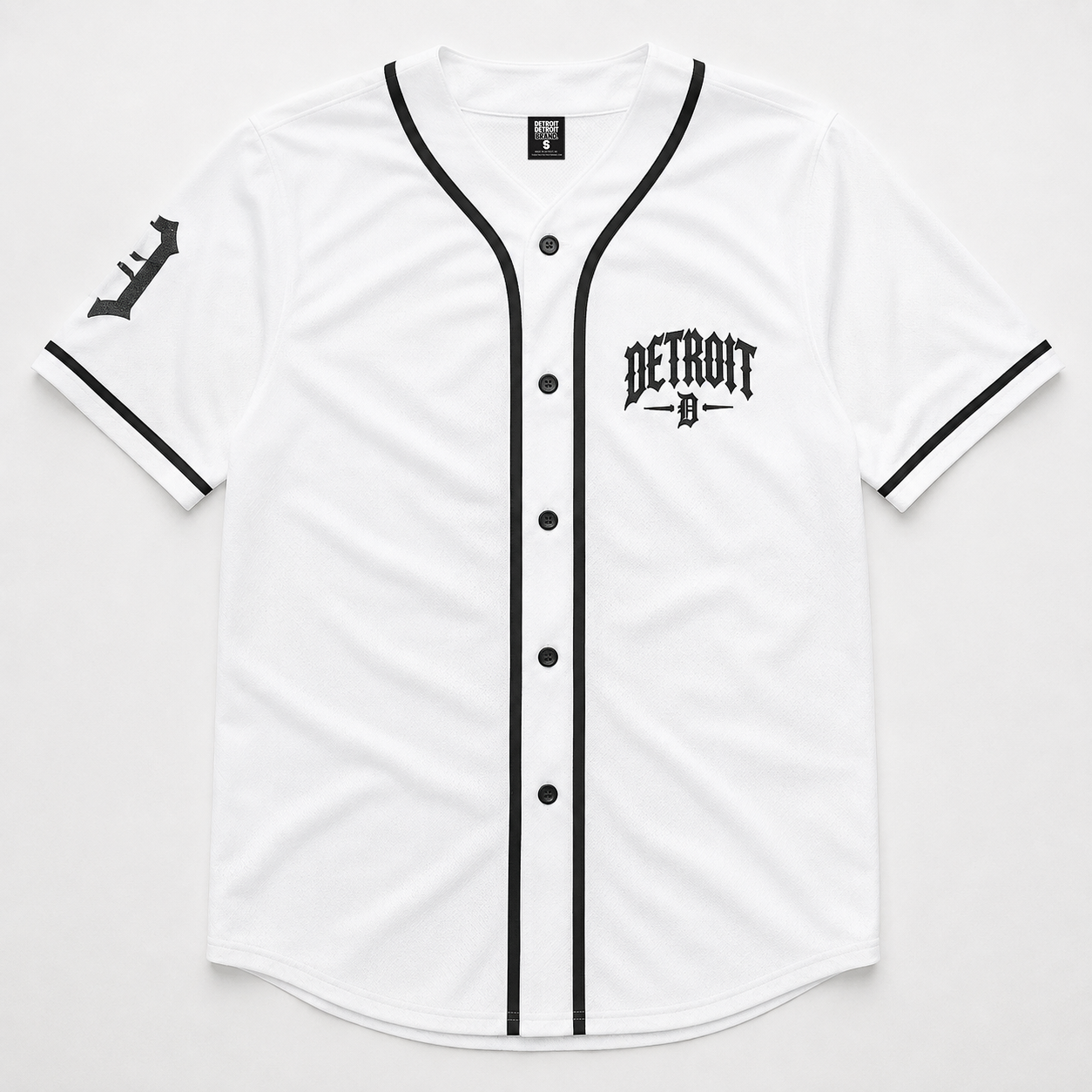 A white short-sleeve baseball-style jersey with black trim, black buttons, a black Detroit logo on the left chest, and a black stylized logo on the right sleeve, shown flat against a light gray background.
